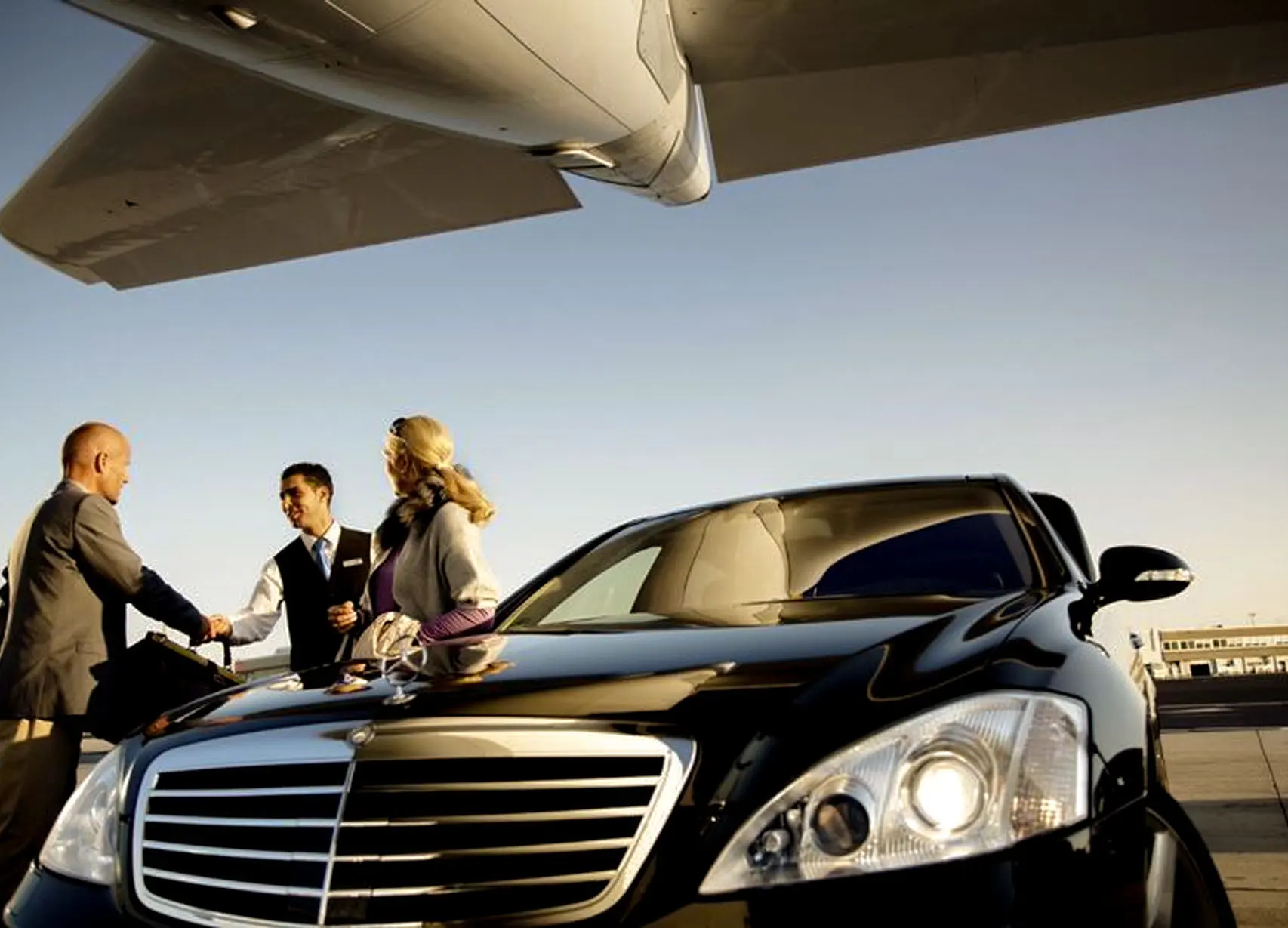 car service to jfk A luxury car parked near a private jet-with people in business attire shaking hands on the tarmac