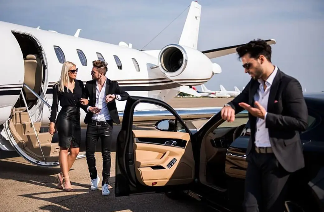 A man and woman are walking out of a private jet while another man stands by a luxury car. limo service in New York