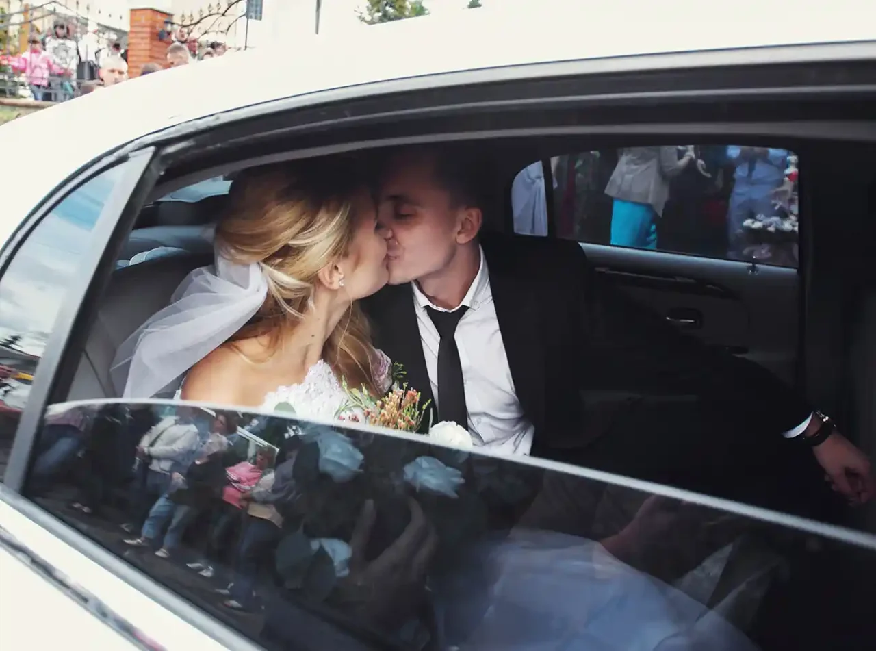 a bride and groom kissing in the back of a car