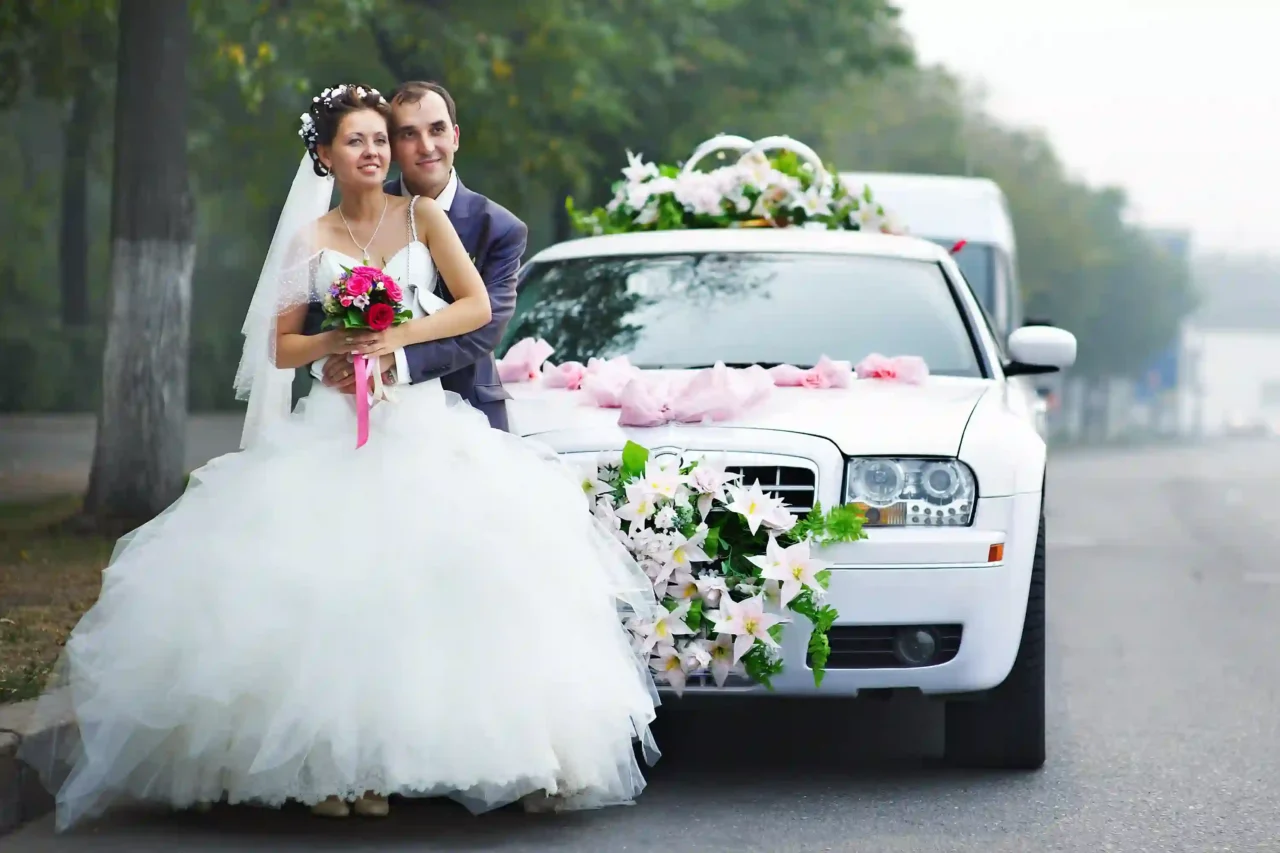 a bride and groom posing in front of a limo All about your limos