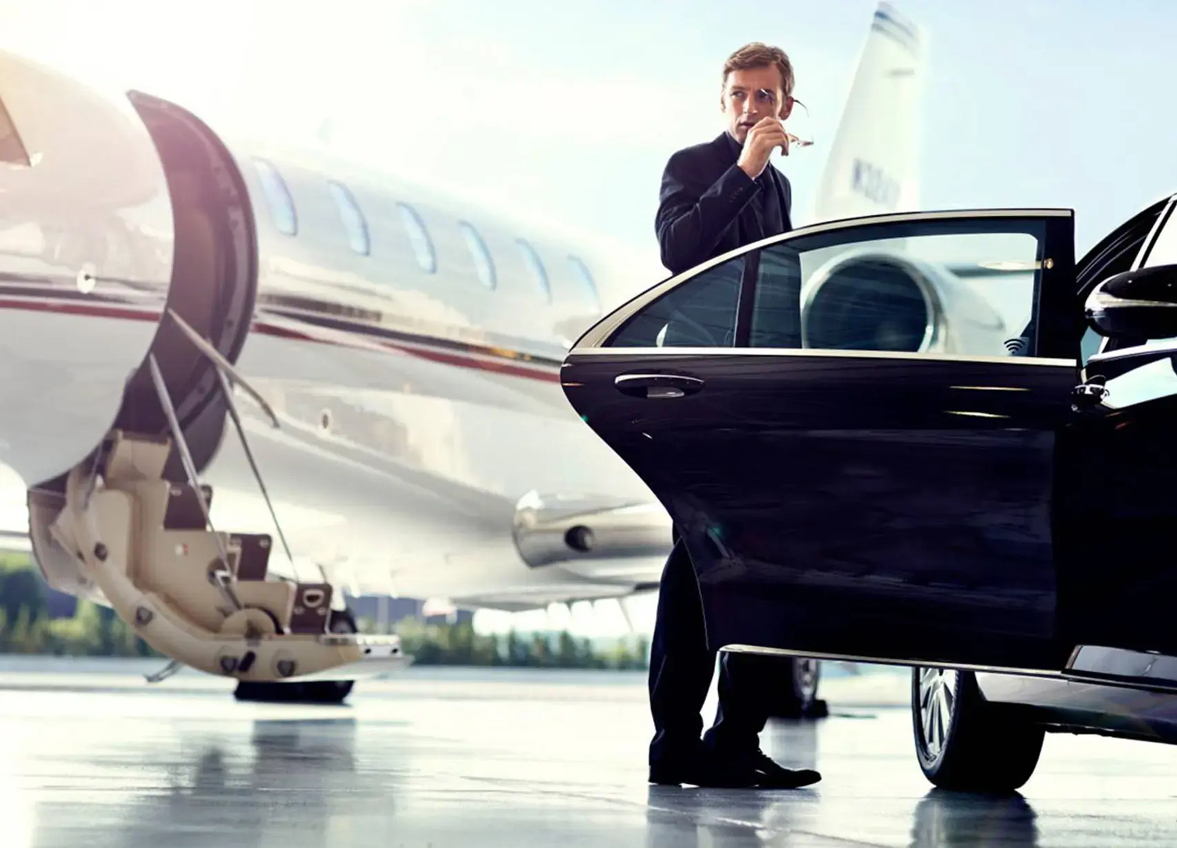 car service to newark airport a man standing in front of a car next to an airplane