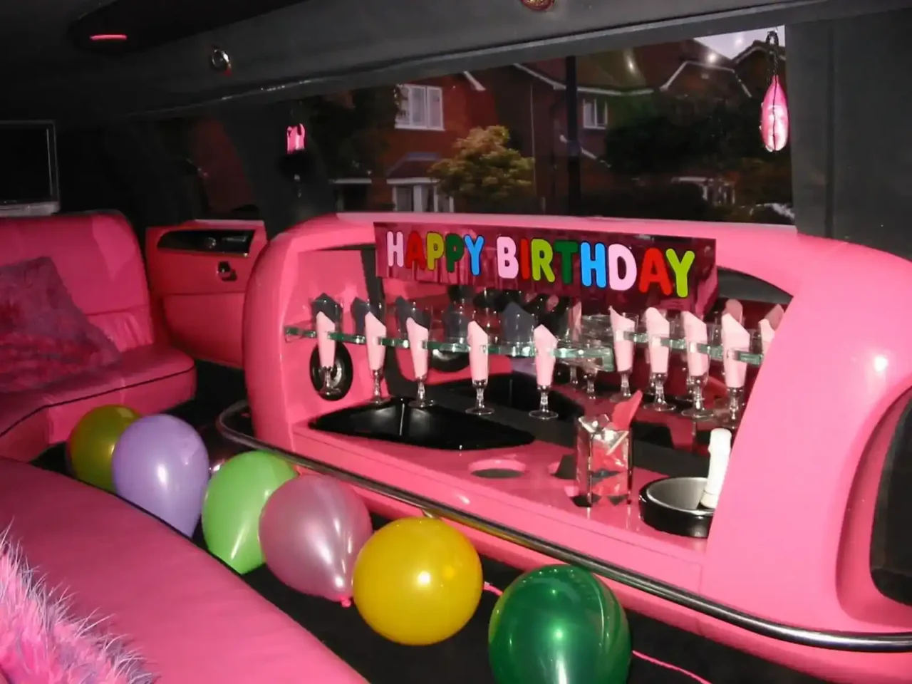 a pink car with balloons and a happy birthday sign 